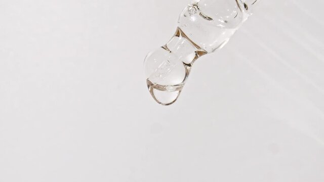 Cosmetic pipette with drops of oil close up on white background. High quality 4k footage