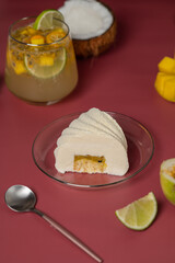 Minimalistic mousse cake with violet white on a pink background. Mousse cake with tropical fruit flavors - mango, coconut, passionfruit, lime.