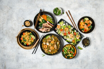 Shrimp salad, fish with vegetables, tom yum, rice with seafood, Asian noodles. Famous Chinese cuisine dishes on table. Top view. Chinese restaurant concept. Asian style banquet.