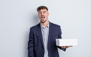 young handsome man with cheerful and rebellious attitude, joking and sticking tongue out. white box...
