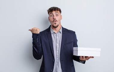 young handsome man looking astonished in disbelief. white box package