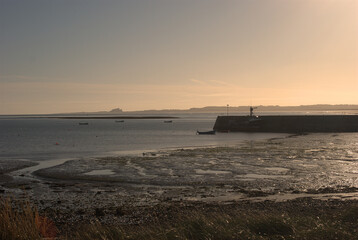 view over Lindisfarne harbour to Bamburgh castle in sunset