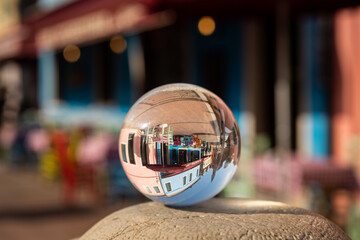 Glass ball lying on pillar in front of colorful houses