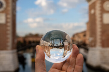 Hand holding glass sphere in front of Arsenale