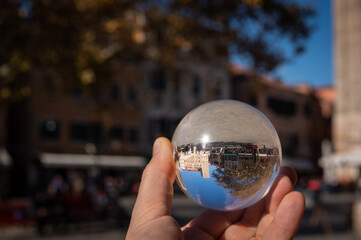 Hand holding glass sphere in front of colorful houses