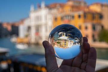 Hand holding glass sphere in front of colorful houses