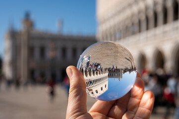 Hand holding glass sphere in front of doge palace