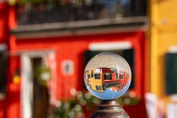 Glass ball lying on pillar in front of colorful houses