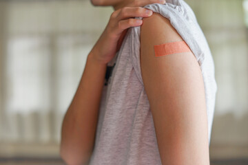 a man pull the sleeve at shoulder show adhesive bandage plaster on his arm after Covid-19 vaccine injection. Free Covid-19 vaccinnation, coronavirus vaccination campaign concept.