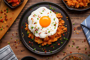 Kimchi Fried rice topped with fried egg and fresh kimchi cabbage in a bowl on placed wooden...