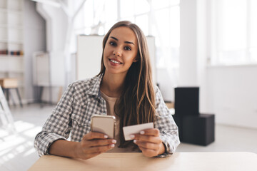 Girl looking on business card and smartphone