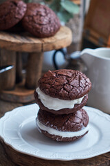 Ice Cream Sandwices: Vanilla ice cream sandwiched between two chocolate cookies on a white plate on a wooden background.