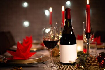 red wine bottle on a christmas holiday festive party table with wine a glass on red and gold shiny...