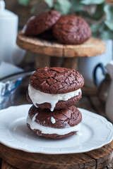 Ice Cream Sandwices: Vanilla ice cream sandwiched between two chocolate cookies on a white plate on a wooden background.