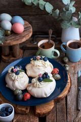 Easter Pavlova cake. Blue, pink eggs, decor, coffee, side view, blueberry.