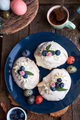 Easter Pavlova cake. Blue, pink eggs, decor, coffee, top  view, blueberry.