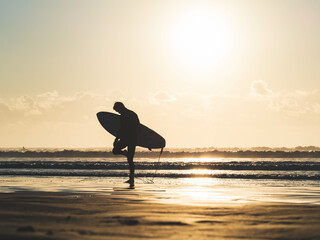 surfer on the beach at sunset