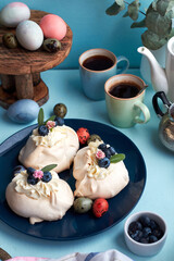 Easter Pavlova cake. Blue, pink eggs, decor, coffee, side view, blueberry.