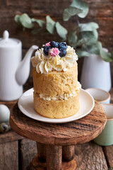 Easter cake with cream, blueberries.  Flowers, blueberry, eggs. Wooden background, side view	