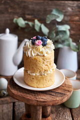 Easter cake with cream, blueberries.  Flowers, blueberry, eggs. Wooden background, side view	