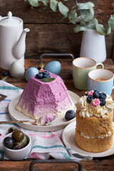 Traditional Easter Orthodox curd cake with blueberry and Easter cake with cream, blueberries.  Flowers, blueberry, eggs. Wooden background, side view	
