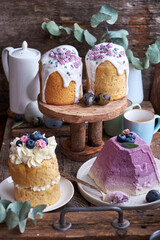 Fototapeta na wymiar Easter cakes with glaze and decorated mini meringue, cream, blueberries and Traditional Easter Orthodox curd cake with blueberry. Wooden background, side view