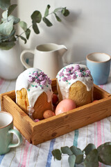 Traditional Easter cake with glaze and decorated mini meringue. White background, side view, pink eggs, pink flowers