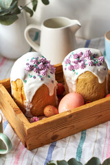 Traditional Easter cake with glaze and decorated mini meringue. White background, side view, pink eggs, pink flowers