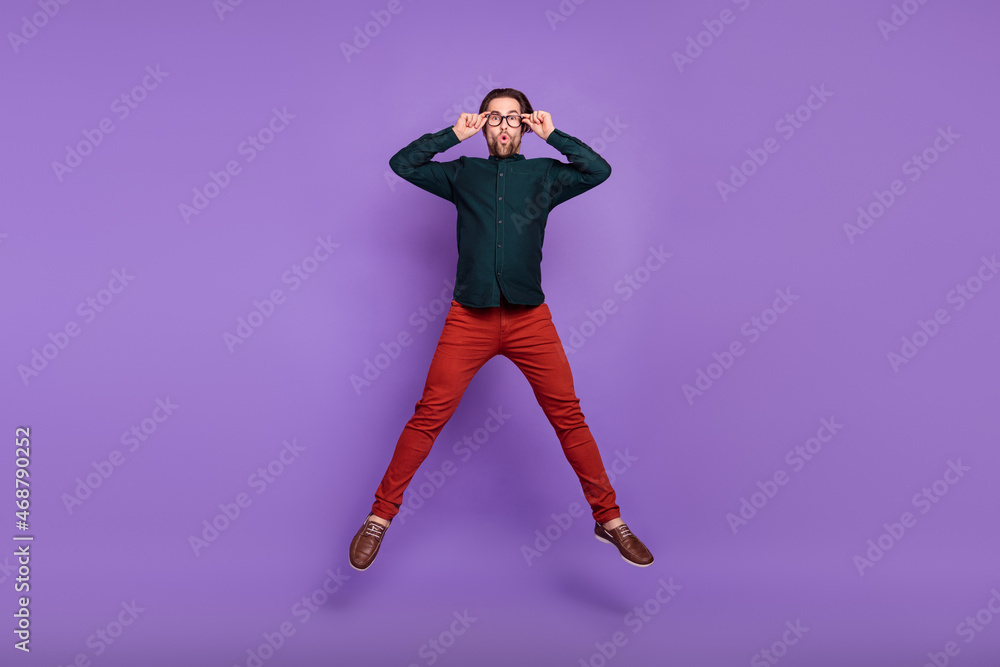 Sticker Photo of funky impressed young guy dressed smart casual clothes jumping high arms spectacles isolated violet color background