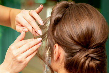 Fototapeta premium Close Up hairdresser stylist makes hairstyle for a young woman in a beauty salon