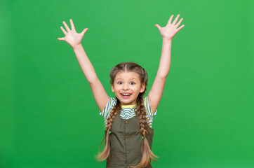 The cheerful little girl raised her hands up. The child is happy on an isolated background.