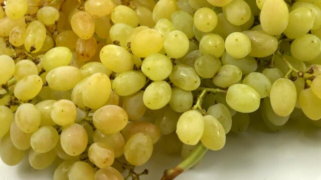 Large bunch of ripe white grapes lies on a white table, background 