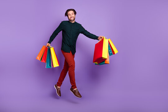 Photo Of Sweet Charming Young Man Wear Smart Casual Outfit Smiling Holding Hoppers Jumping High Empty Space Isolated Purple Color Background