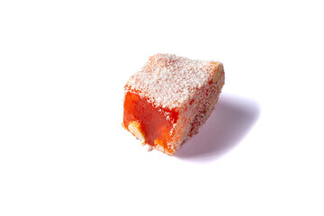 Turkish delight isolated on white background. Orange lokum covered coconut flakes. Fruit jelly candy with hazelnut. close up