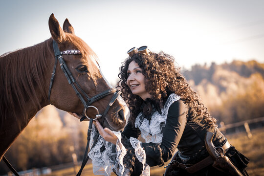 Portrait of a mature woman in a steampunk costume with a horse against the backdrop of an autumn landscape.
