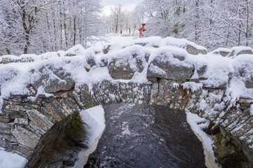 Old arch bridge crossing a river in a winter landscape