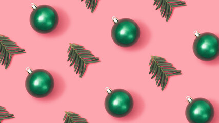 Trendy New year pattern with green Christmas baubles and fir branches on pastel pink background.