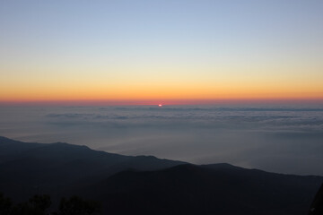 Sunrise seen from the mountains. Sun on the horizon above the clouds