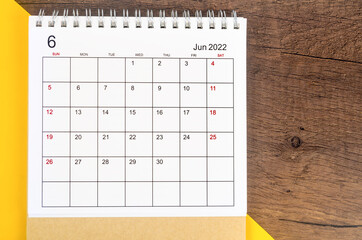 June 2022 desk calendar on wooden table.