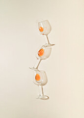 Minimal flat lay composition with three rose vine glasses on bright cream background.