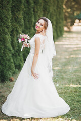 Fototapeta na wymiar Beautiful luxury young bride in wedding dress posing in park