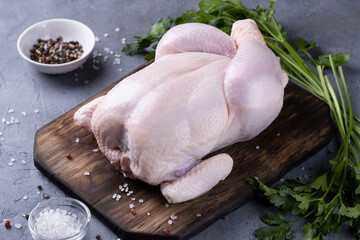 whole raw chicken on a wooden board