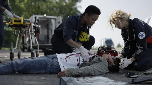 Team of paramedics providing support for victim on road