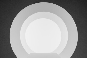 White and dark grey abstract scene with podium, circles tunnel or arches with perspective, light as stage template in minimal geometric style for presentation products, advertising, design.