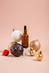 Christmas minimalistic composition with brown glass serum bottle on pastel background with golden balls. Health and beauty concept.