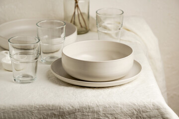 Scandinavian nordic style. Set of different modern white empty   ceramic tableware and glasses. Ceramic plates on white, flax rose tablecloth background. Overview empty food table with tableware