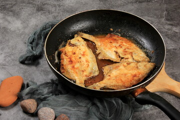 Three fried flounder fish on metal frying pans. Fried fish in a pan 