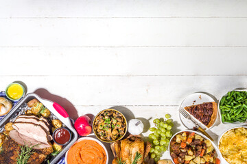Thanksgiving dinner table with new traditional thanksgiving food - chicken, mashed sweet potatoes, green beans, pecan pie, baked ham pork, mac and cheese, stuffing, modern hard sunny light flatlay
