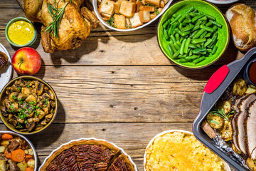 Thanksgiving dinner table with new traditional thanksgiving food - chicken, mashed sweet potatoes, green beans, pecan pie, baked ham pork, mac and cheese, stuffing, modern hard sunny light flatlay
