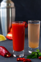 close-up tomato cocktail.two tequila shots on black background. Sangrita is Mexican traditional alcohol drink with tequila, tomato juice, hot spices, chili pepper and lime.copy space.alcoholic drink.